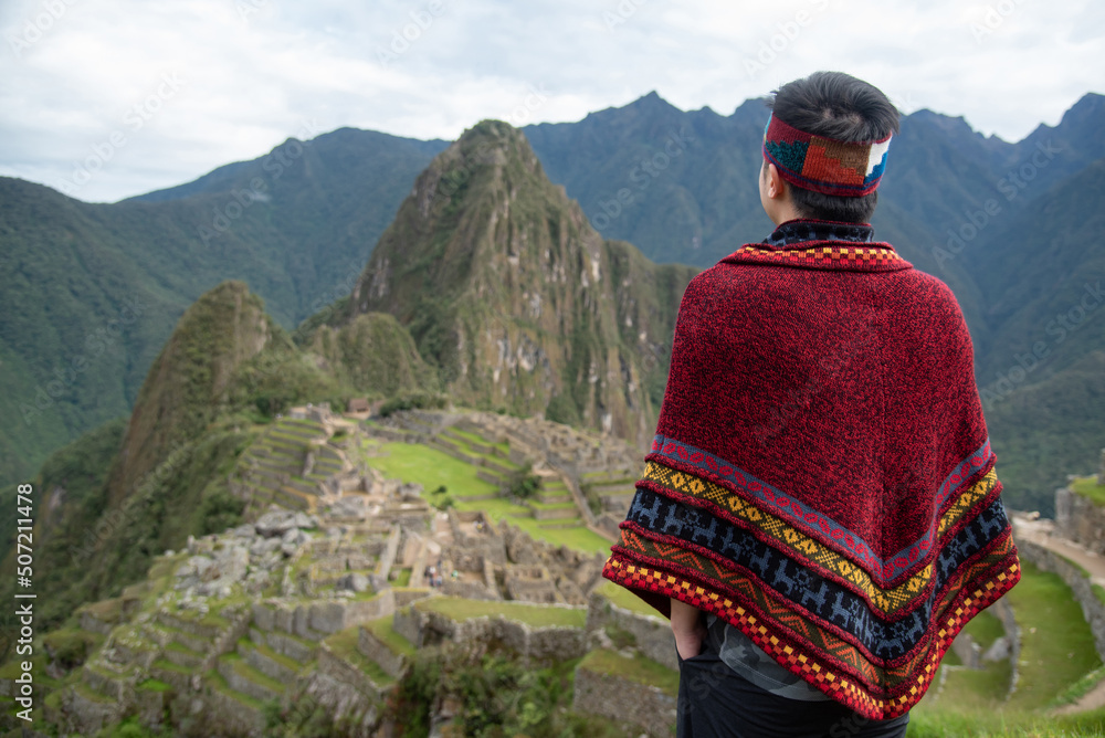 Asian man tourist in traditional Peruvian clothing looking at Machu ...