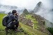 © zephyr_p - Asian man tourist and photographer taking photo at Machu Picchu, one of seven wonders and famous tourist attraction in Cusco Region of Peru. This majestic place has known as Lost City of the Incas.