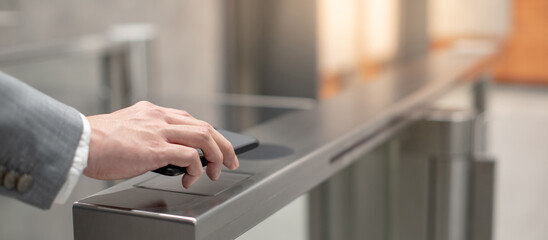 Businessman hand with business wear using smartphone to open automatic gate machine in office building. Working routine concept