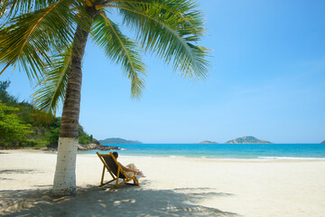 Sticker - Woman under palm tree reading book at beach resort during summer vacation