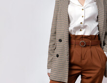 Fashionable Women S Casual Spring Outfit . Business Concept. A Woman In A Tweed Jacket, Brown Trousers With A Belt. Holds His Hand In His Pants Pocket With Space For Text. Empty Space Under The