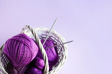 Purple Lilac Balls Of Thread With Knitting Needles In A Basket On A Lilac Background For Knitting Warm Clothes, Hobbies