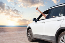 Hand Showing Thumb Up Out Window Car On Blue Sky, White Clouds, Sun And Sea Background
