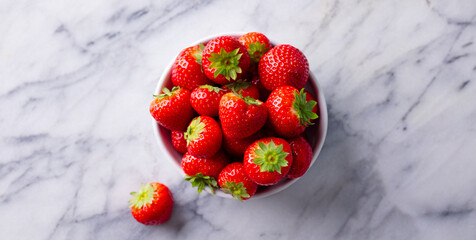 Wall Mural - Fresh strawberries in white bowl. Marble background. Close up. Top view.