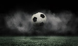 Fototapeta Sport - Soccer ball jumping on green grass of football field isolated on dark background with smoke. Concept of sport, art, energy, power. Creative collage. World cup concept