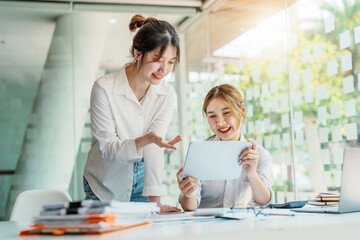 Wall Mural - Negotiation, Analysis, Discussion, Portrait of an Asian women economist and marketer using tablet computer to plan investments and financial to prevent risks and losses for the company