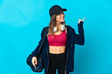 Wall Mural - Young sport woman with sport bag isolated on blue background pointing up a great idea