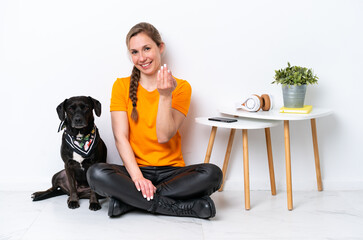 Wall Mural - Young caucasian woman sitting on the floor with his puppy isolated on white background inviting to come with hand. Happy that you came