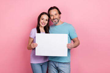 Poster - Portrait of two cheerful positive people hold demonstrate empty space list isolated on pink color background