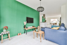 Bright Flat Living Room Interior With Blue Couch And TV Hanging On Green Wall