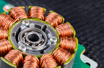 Electric engine stator with coils copper wire winding or ball bearing on green PCB detail. Closeup of step motor inductors or metal ferromagnetic sheets from laser printer machine on blurry black net.