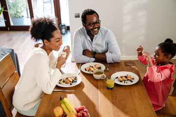 Wall Mural - African american woman and man with daughter having breakfast at home