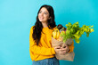 © luismolinero - Young woman holding a grocery shopping bag isolated on blue background thinking an idea while looking up