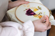 Cross-stitch embroidering in progress. Young girl in linen clothes is doing handmade embroidery