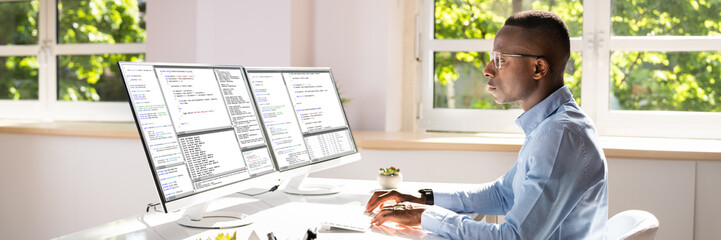 African American Coder Using Computer At Desk
