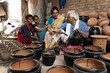 Happy Indian family of potters painting clay pots at workshop