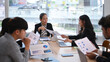 © Prathankarnpap - Middle aged female team leader explaining project details, discussing for new strategy of development with young employees at meeting