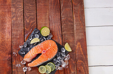 Wall Mural - Red fish steak on a wooden brown table with lime slices and ice. Trout steak on a brown background. Healthy food