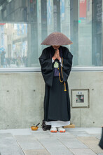 Buddhist monk wearing 'takuhatsugasa' woven rice-straw kasa hat and chanting mantras in Tokyo, Japan