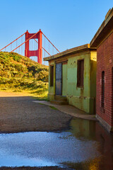 Wall Mural - Golden Gate Bridge peaking over hills by path lined with old structures