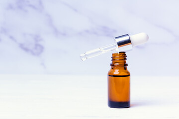 Essential oil in a bubble with a pipette on a white marble background