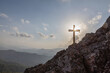 Silhouettes of crucifix symbol on top mountain with bright sunbeam on sunset sky background