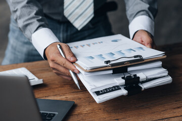 Poster - Businessman holding a pile of company financial documents, he is checking company finances before attending a meeting with the finance department. Concept of corporate financial management.