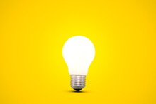 Glowing Light Bulb Isolated On A Bright Yellow Background.