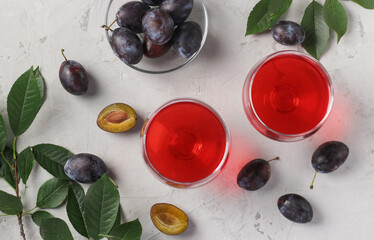 Homemade plum liqueur in two glasses on light gray background