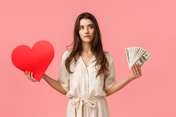 Wall Mural - Romance, wealth and modern lifestyle concept. Alluring good-looking brunette female in dress, holding cash, money and love heart, biting lip look upper right corner unsure, making decision