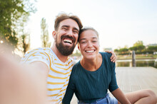 Mobile Phone Selfie Of A Young Adult Caucasian Couple Looking Camera. Happy Boyfriend And Smiling Girlfriend Having Fun Together