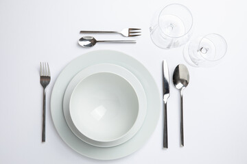 Empty white plate with spoon, knife and fork on white background