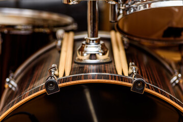 A close view of a drum kit set up for recording in a recording studio with drum sticks placed on the bass drum