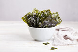 Fototapeta  - Crispy nori seaweed on bowl on grey background. Traditional Japanese dry seaweed sheets. Healthy snack. 