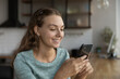 © fizkes - Happy beautiful gen Z teen girl chatting on smartphone online, reading text on screen, typing message, making video call. Young woman using app on cellphone at home, shopping on internet