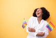© Chalermphon - Portrait of African girl holding LGBT flag standing yellow background studio.American LGBTQ woman with gay flag. Woman look smart bright and energetic cheerful.Gender equity,anti violence concept.