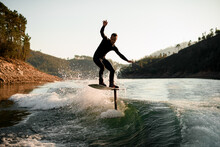 Athletic Man Skillfully Balances On Splashing Wave On A Foil Wakeboard