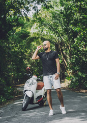 Wall Mural - Stylish young man and his motorbike on the road in the jungle