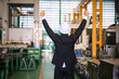 © Blanscape - Rear of Asian business owner raise hands in factory warehouse