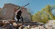A Ukrainian soldier with a rifle pointed in front of him leaves the destroyed house and aims at the sides