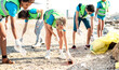 Young volunteers wearing uniform at beach shore cleaning activity from trash garbage - Environment conservation concept for plastic material pollution with organized people group - Bright vivid filter