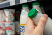 Buyer Checks Expiration Date Of Dairy Product Before Buying It. Hand Holding Milk Bottle In Supermarket.