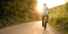 Teenager Riding A Bicycle On The Road Summer Sunlit