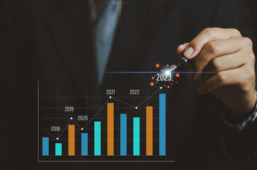 Analysis of business growth trends and company finances Businessman working with virtual screen graph and chart. arrow pointing to 2023