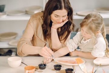 Portrait of mother and little girl shaping clay together