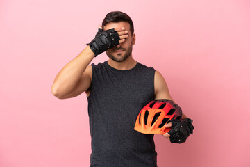 Wall Mural - Young cyclist man isolated on pink background covering eyes by hands. Do not want to see something