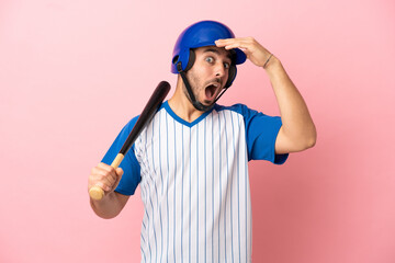 Wall Mural - Baseball player with helmet and bat isolated on pink background doing surprise gesture while looking to the side