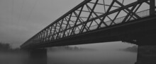 Silhouette Of Bridge Over River Covered With Mist In Black And White