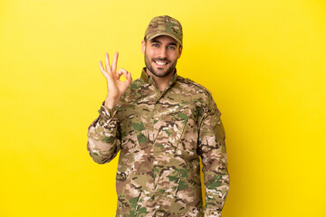 Wall Mural - Military man isolated on yellow background showing ok sign with fingers