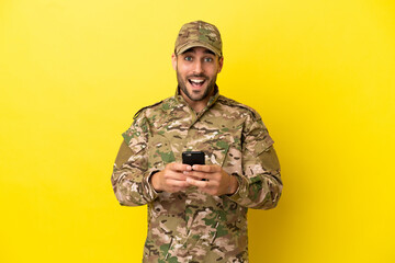 Wall Mural - Military man isolated on yellow background surprised and sending a message